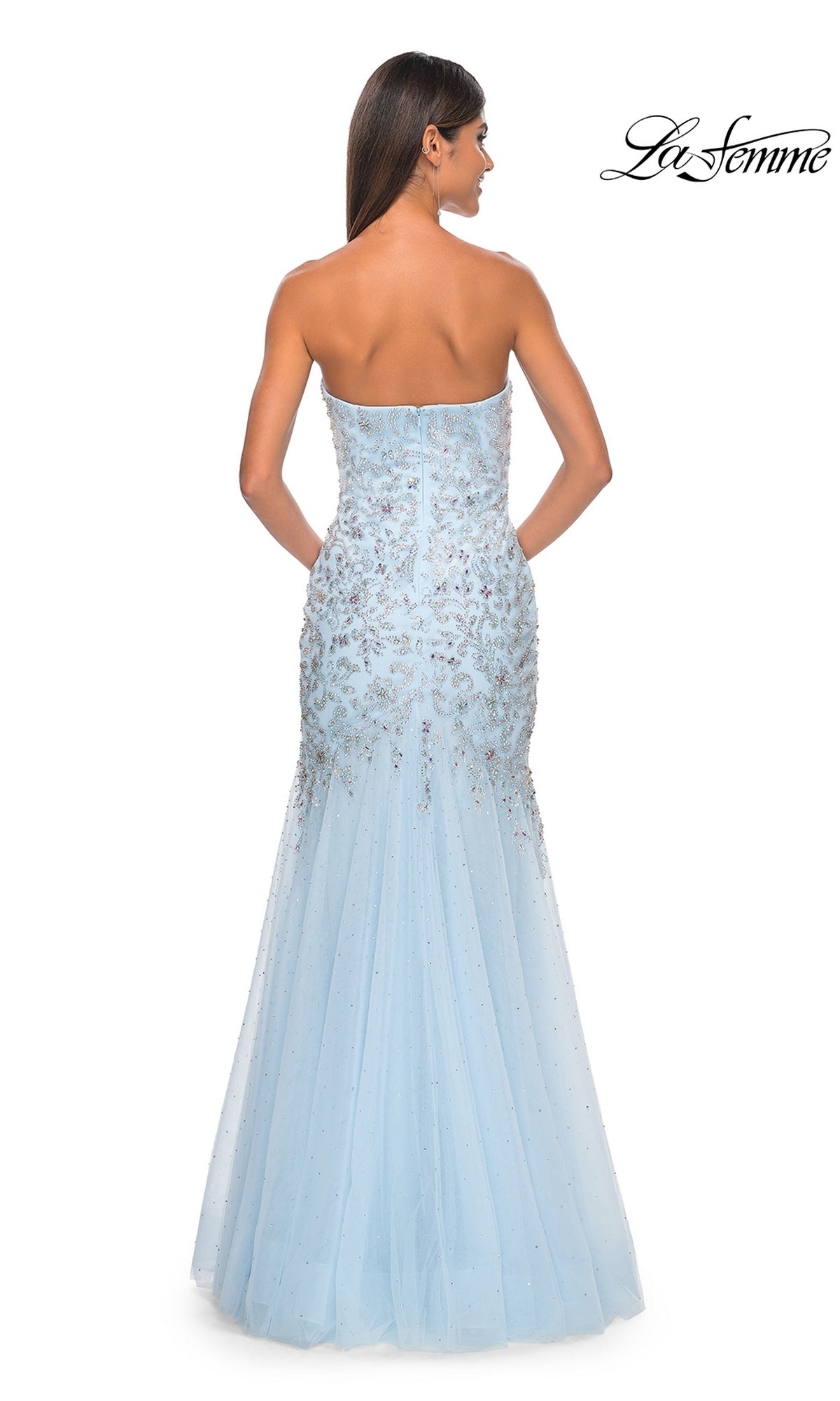 A woman models the La Femme Strapless Long Beaded Prom Dress 32197 in light blue, featuring a floor-length mermaid silhouette with sequin embellishments, elegantly shown from the back.